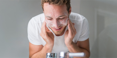 A man washing his face over the sink.