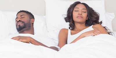 A couple napping in bed next to one another.