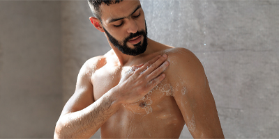 Man cleansing himself with Pevonia's Bath & Body products in the shower.