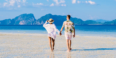 A couple walking along the beach on a bright summer day.